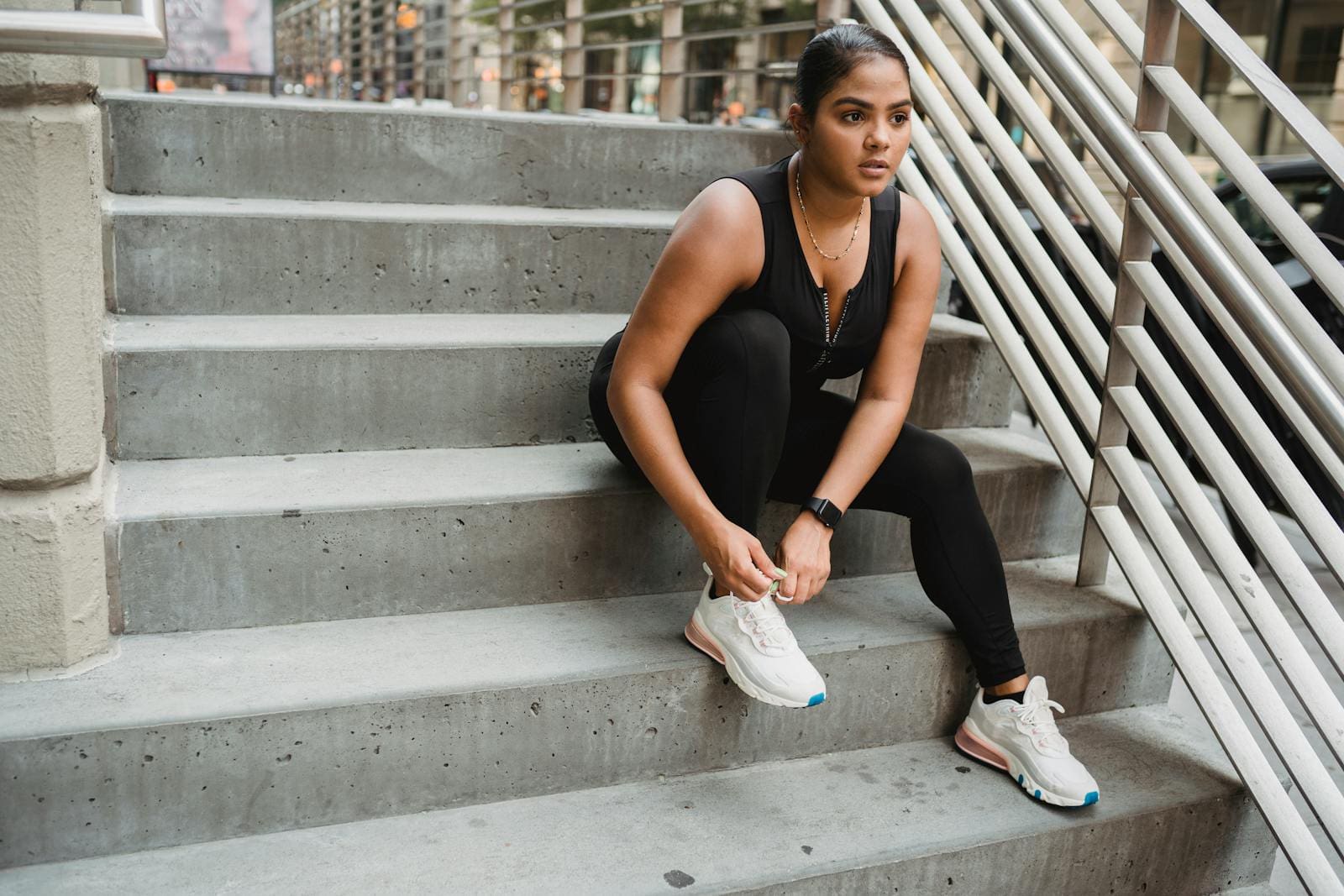 Woman in Sports Clothing Sitting on Stairs and Tying Her Shoe